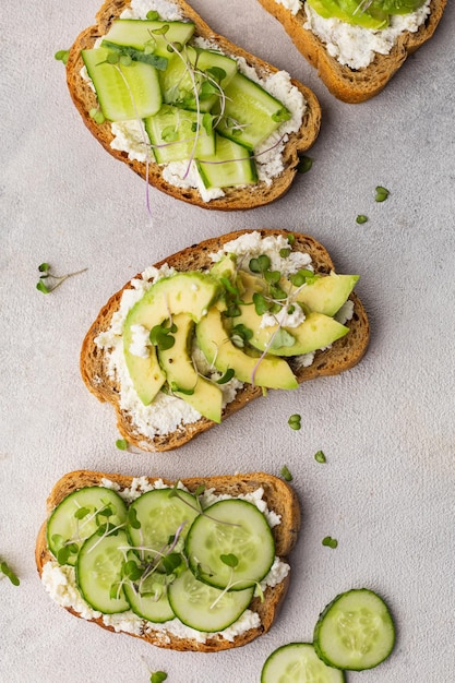 Sanduíches verdes vegetarianos com abacate e pepino com microgreens em um fundo claro