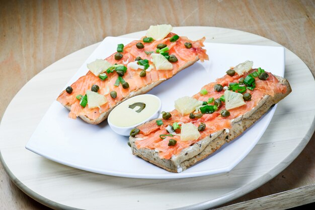 Sandvich de salmón en plato blanco.