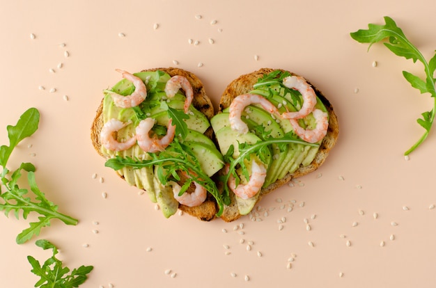 Sandwich abierto con aguacate, gambas y rúcula en forma de corazón