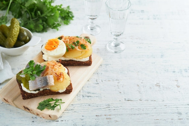 Sándwich abierto o smorrebrod con pan de centeno, huevos de arenque, cebollas caramelizadas, perejil y requesón sobre fondos de mesa rústica de madera antigua Comida tradicional danesa o escandinava