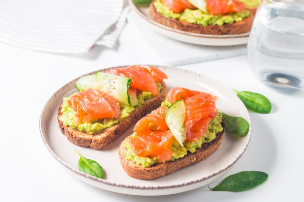 Sándwich abierto con salmón ahumado y salado para un desayuno saludable. Trucha y aguacate sobre bruschetta t