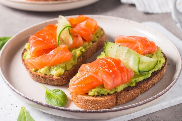 Sándwich abierto con salmón ahumado y salado para un desayuno saludable. Trucha y aguacate sobre bruschetta t