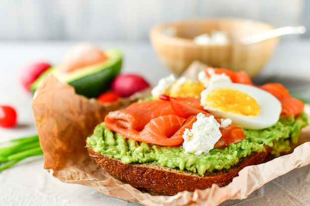 sandwich con aguacate y salmón sobre un fondo claro