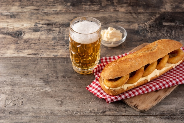 Sándwich de anillos de calamares y cerveza en la mesa de madera