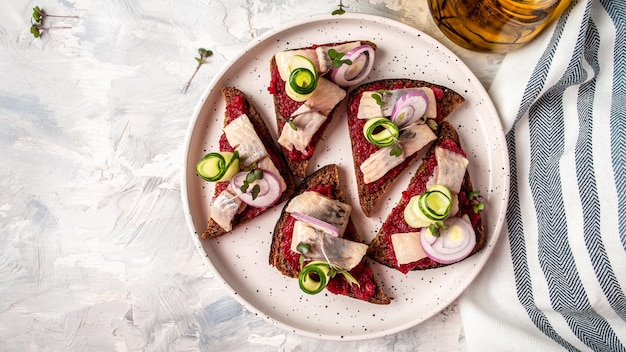 Sándwich con arenque, remolacha, pepino verde, cebolla y microverde Tostadas de pan oscuro Tradición Cocina escandinava danesa Vista superior de formato de pancarta larga