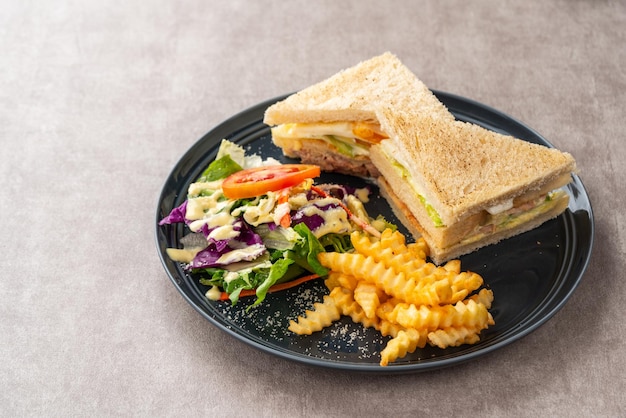 Sándwich de atún con papas fritas y ensalada.