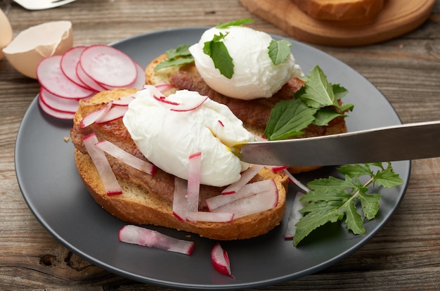 Sandwich auf gerösteter weißer Scheibe Brot mit pochierten Eiern, grün