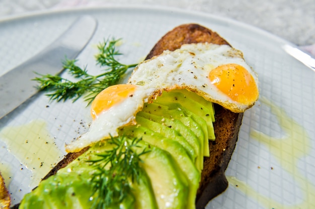 Sándwich de avacado con huevo sobre tostadas de pan negro.