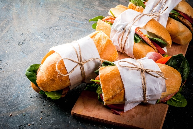 Sándwich de baguette fresco con tocino, queso, tomate y espinacas.