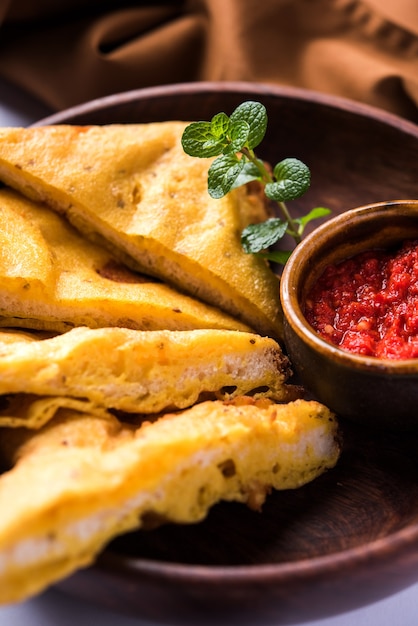 Sandwich Bread Pakora oder Pakoda (Dreiecksform) serviert mit Tomatenketchup, Chutney, grünen Chili- und Zwiebelscheiben, beliebter indischer Snack zur Teezeit. Selektiver Fokus