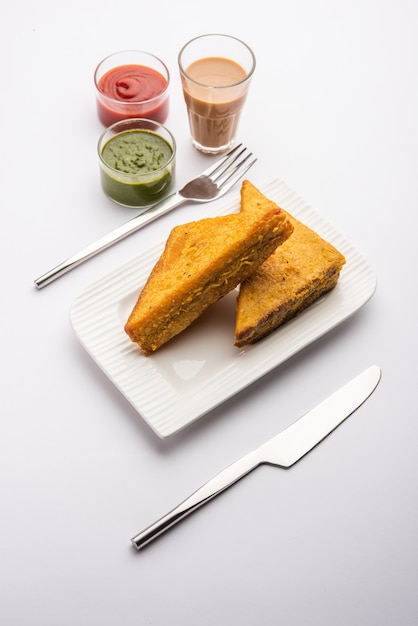 Sandwich Bread Pakora oder Pakoda in Dreiecksform, serviert mit Tomatenketchup, grünem Chutney, beliebter indischer Snack zur Teezeit