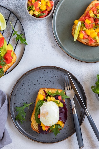 Sándwich de brioche con salmón aguacate huevo escalfado y salsa de mango con rúcula y ensalada