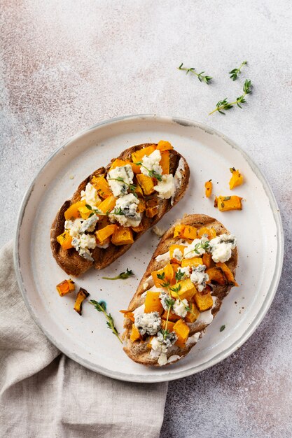 Sandwich de calabaza al horno con queso dorblu con moho azul y tomillo sobre un fondo de hormigón