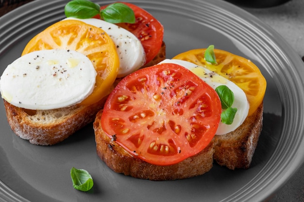 Foto sandwich caprese con pan de centeno tomates mozzarella y albahaca fresca en un plato gris comida saludable