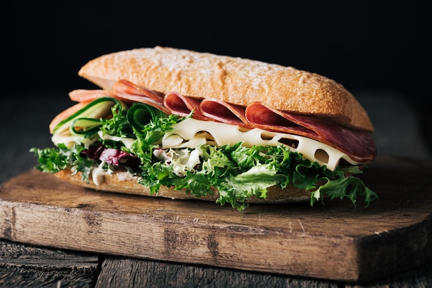 Sándwich casero con queso de jamón y lechuga en un enfoque selectivo de tablero de madera rústica