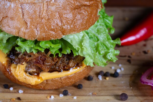 Foto sándwich de cerdo con lechuga, tomate y queso cheddar servido en una tabla de madera negra sándwich artesanal hecho a mano