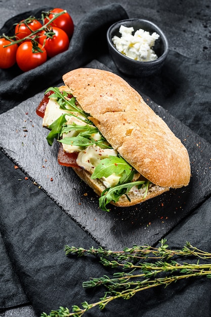 Sándwich de chapata con queso de cabra fresco, mermelada de pera y rúcula. vista superior.