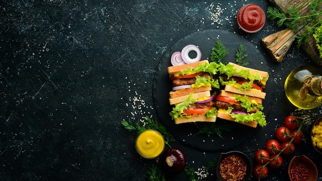 Sándwich con chuleta de queso y lechuga sobre un fondo de piedra negra Comida callejera Vista superior Espacio de copia libre