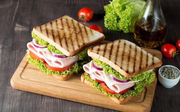 Un sándwich club con carne, ensalada, verduras.