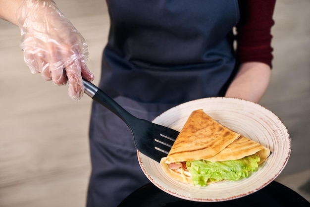 Sándwich de crepé enrollado con verduras y servido en un plato blanco Desayuno caliente tradicional Vista de cerca