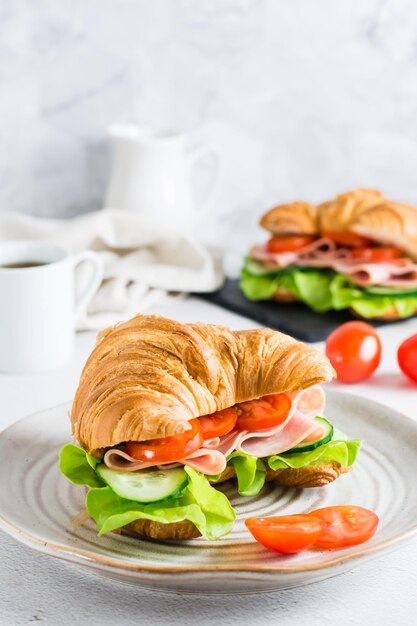 Sándwich de croissant fresco con verduras de jamón y lechuga en un plato Vista vertical