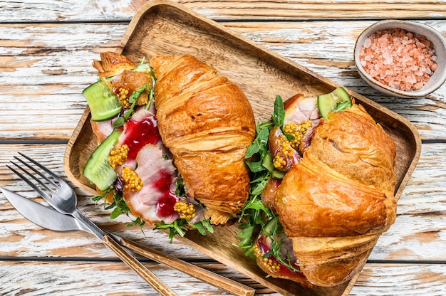 Sandwich Croissant mit Schinken und Käse auf Holzbrett