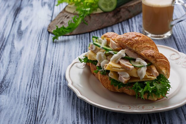 Sándwich de croissant con pollo, queso y pepino.