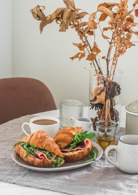 Sándwich de croissant con rúcula de queso crema de jamón de pavo en una cocina acogedora