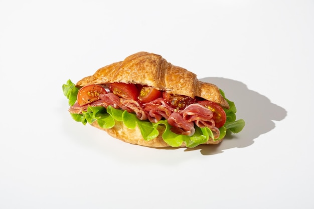 Foto sándwich de croissant con tocino y tomate aislado sobre fondo blanco