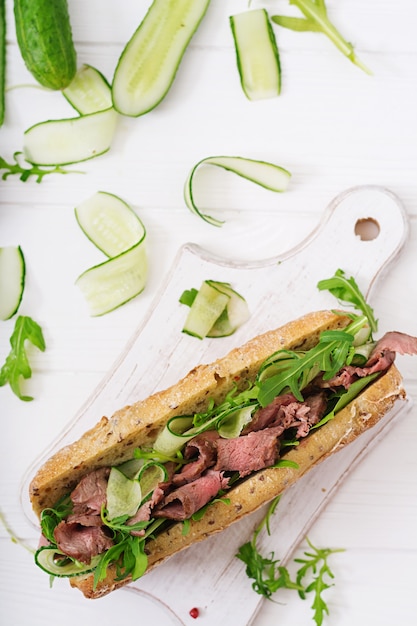 Sandwich des Vollweizenbrotes mit Roastbeef, Gurke und Arugula. Draufsicht. Flach legen.