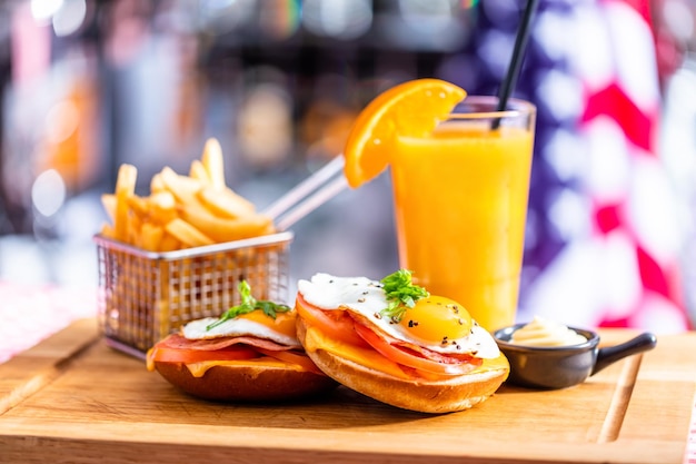 Sándwich de desayuno americano con huevo frito papas fritas y jugo de naranja