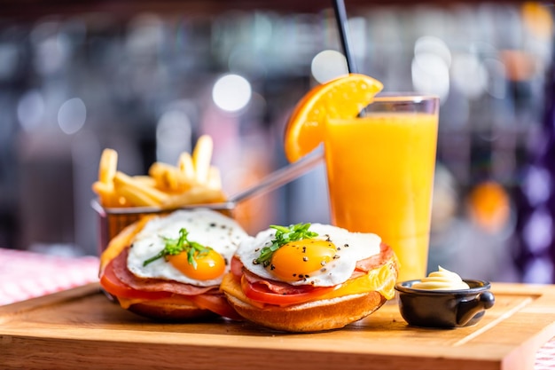 Sándwich de desayuno americano con huevo frito papas fritas y jugo de naranja