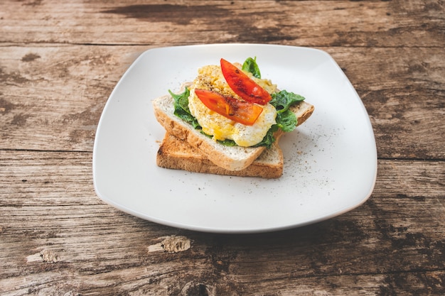 Sándwich de desayuno con huevo, berros y tomate en la mesa de madera, alimentos saludables