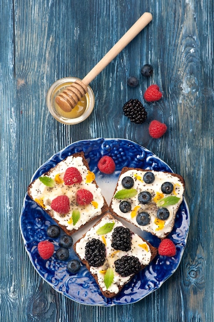 Sándwich dulce con bayas, frutas, queso crema, semillas de chía y miel, desayuno saludable Vista superior