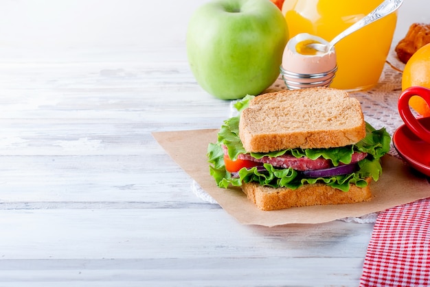 Sandwich, Ei, Tasse Kaffee und ein Glas Saft zum Frühstück