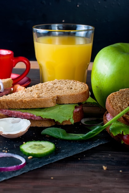 Sandwich, Ei, Tasse Kaffee und ein Glas Saft zum Frühstück