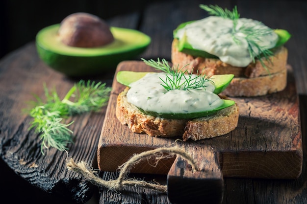 Sándwich con eneldo de aguacate y salsa tzatziki sobre mesa de madera