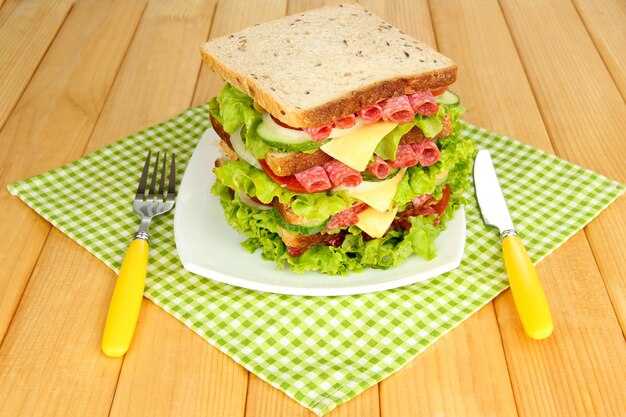 Sándwich enorme en mesa de madera sobre fondo brillante