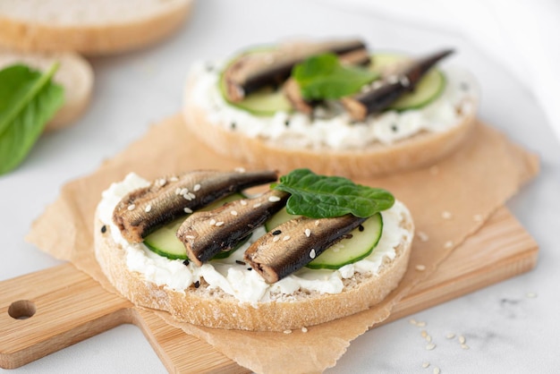 Sándwich con espadines requesón y pepino en un primer plano de tablero de madera