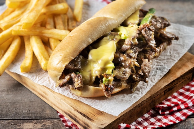 Sándwich de filete de queso de Filadelfia con pimientos verdes de queso de res y cebolla caramelizada aislado sobre fondo blanco