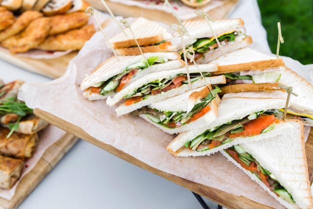 Sándwich de forma triangular con verduras de jamón y mayonesa en un plato de madera Menú para un evento al aire libre en verano Foto horizontal