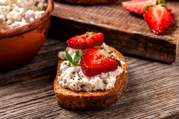 Sandwich con fresas, queso ricotta y miel, chia sobre fondo de madera