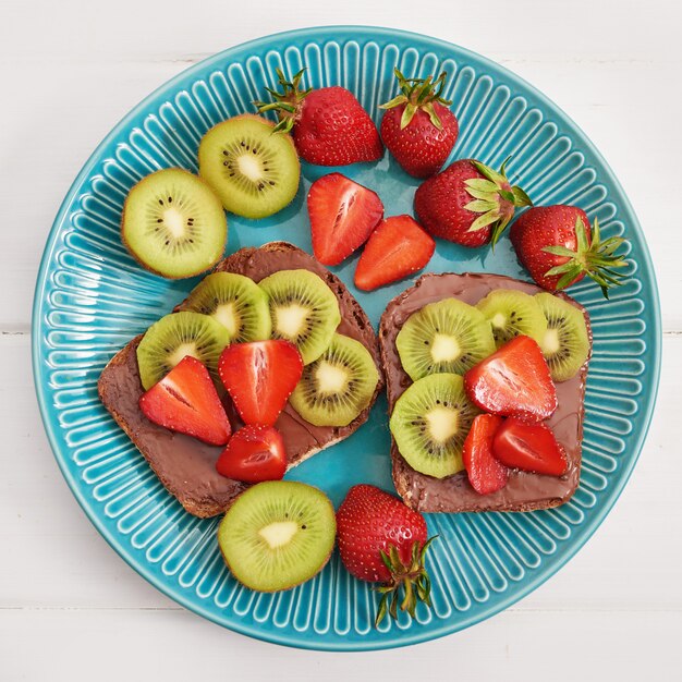 Sandwich de frutas, fresas y kiwi. Tostadas de mantequilla de maní.