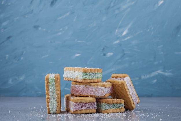 Sándwich de galleta relleno de mermelada de colores sobre fondo de piedra.