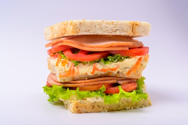 Sándwich grande con crema de jamón ahumado lechuga y tomate aislado sobre fondo blanco comida rápida