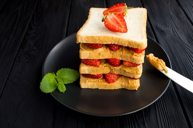 Sándwich grande con fresa y mantequilla de maní en la placa negra