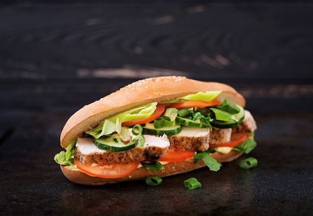 Sándwich grande con pechugas de pollo, tomate, pepino y hierbas.