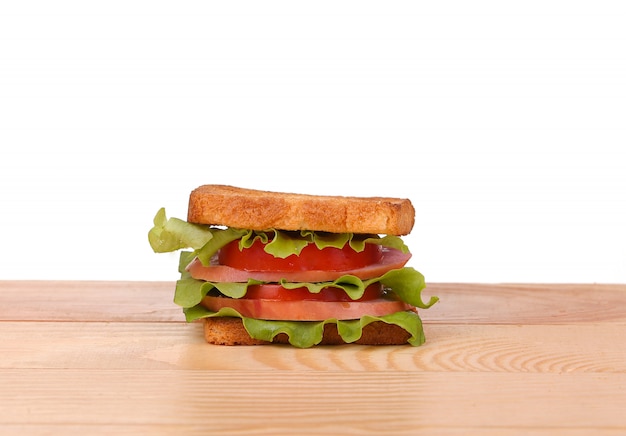 Sándwich grande con verduras frescas sobre tabla de madera en blanco