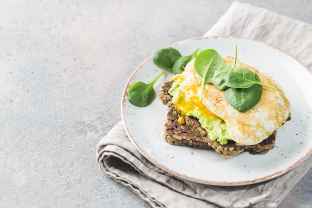 Sándwich con huevo de aguacate y espinacas sobre fondo de madera blanca desayuno dieta saludable