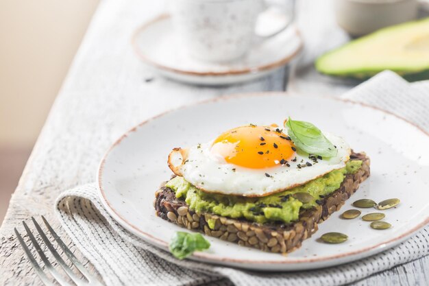 Sándwich con huevo de aguacate y espinacas sobre fondo de madera blanca desayuno dieta saludable